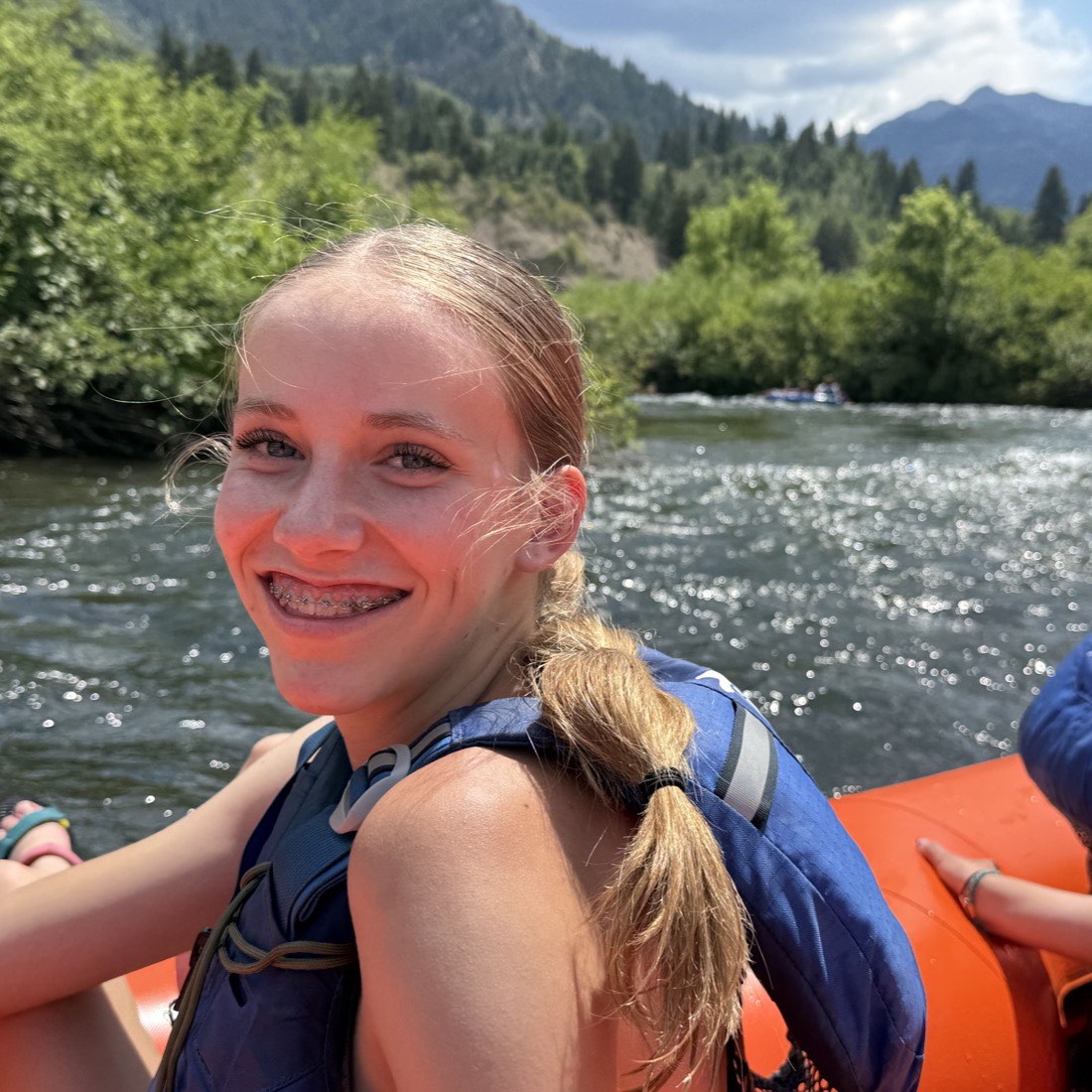 A student smiling on a raft during the MVF Students summer river trip