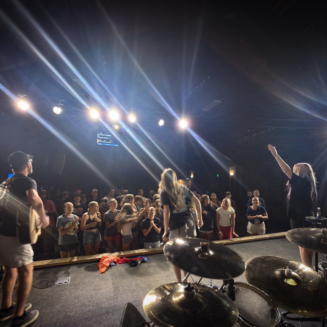 Students worshipping under stage lights on a Wednesday night at MVF Students